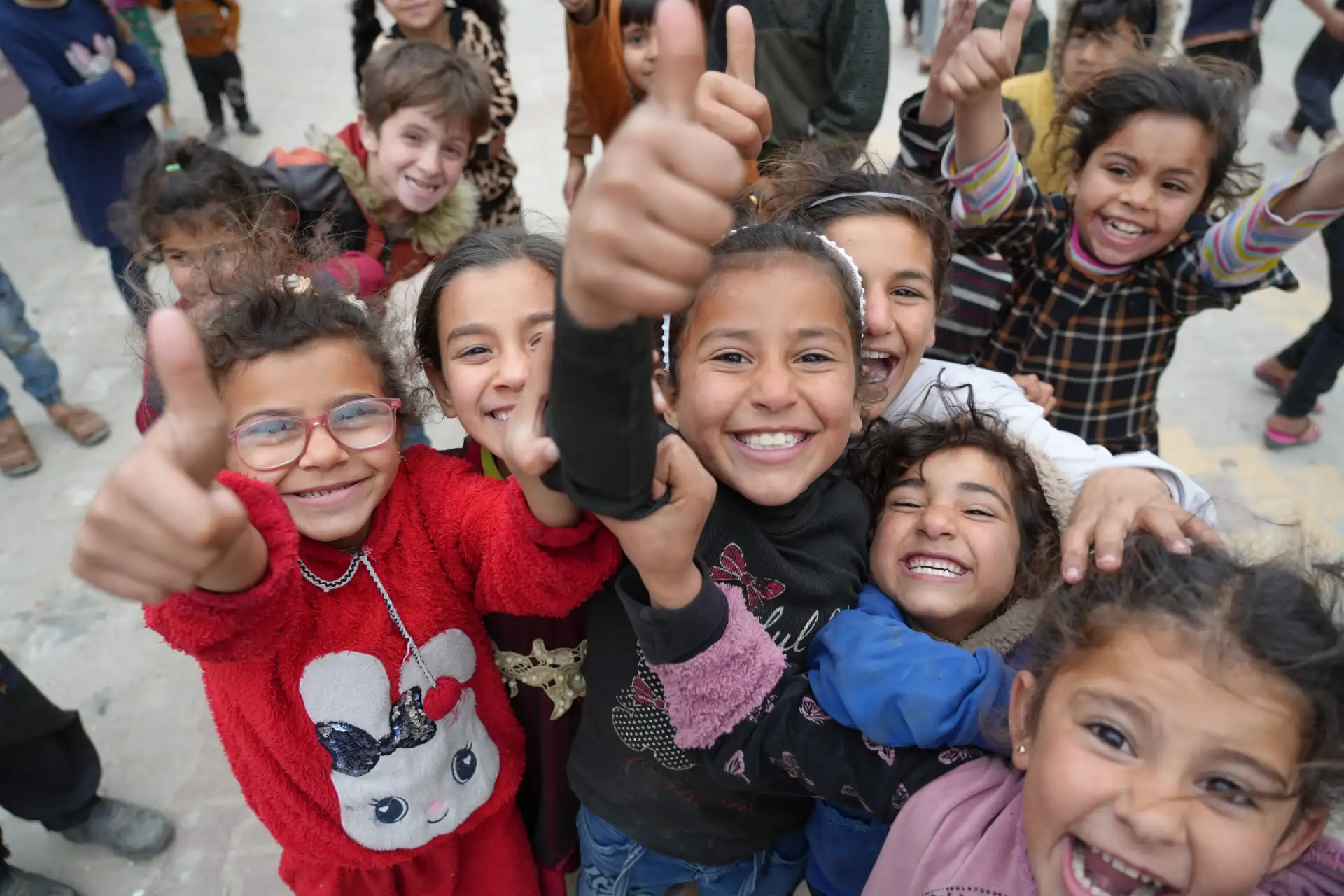 A group of smiling children in an HDF program giving thumbs up to the camera